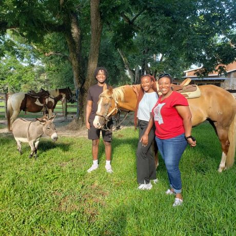 family posing for photo with a horse and donkey at Green Woods Stables RV Park