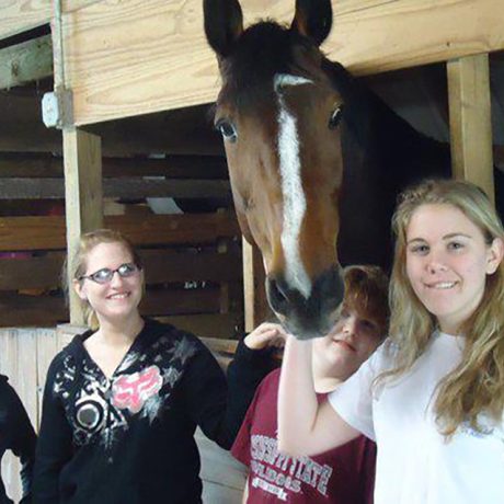 girls with a horse in the stable